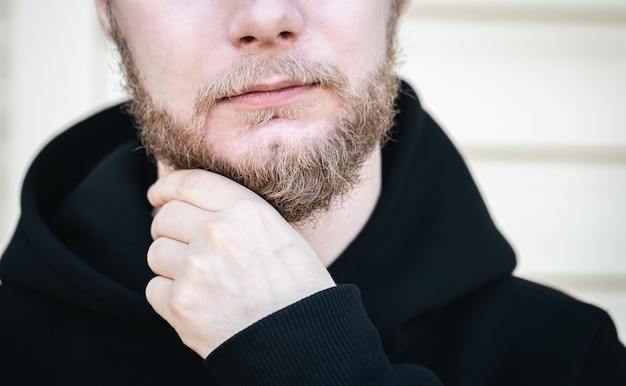 Gratis foto close-up een jonge man raakt zijn baard aan met zijn hand