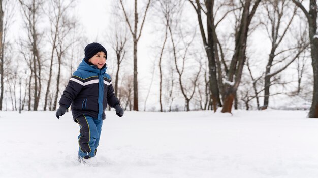 Close-up en gelukkig kind spelen in de sneeuw