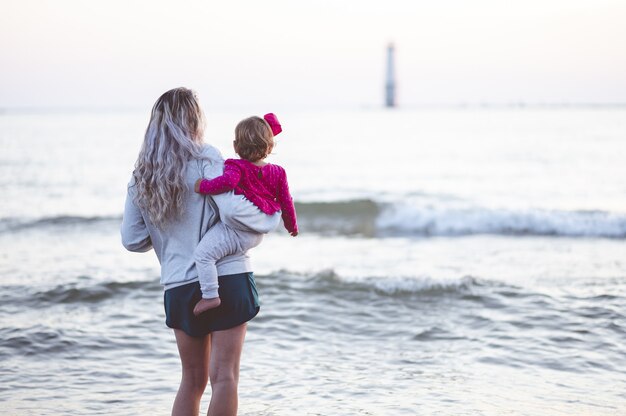 Close-up focus shot van achteren van een moeder en haar kind kijken naar de zee