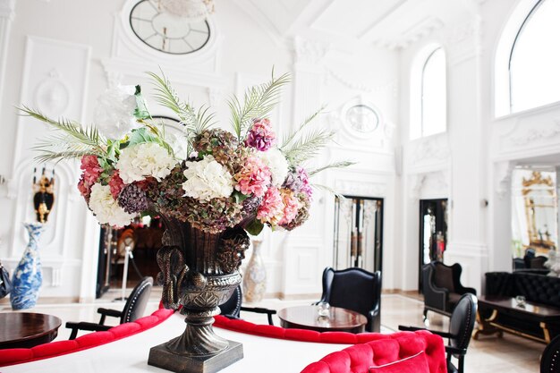 Close-up foto van een enorm boeket gemaakt van hortensia's die op tafel staan in een grote luxe kamer