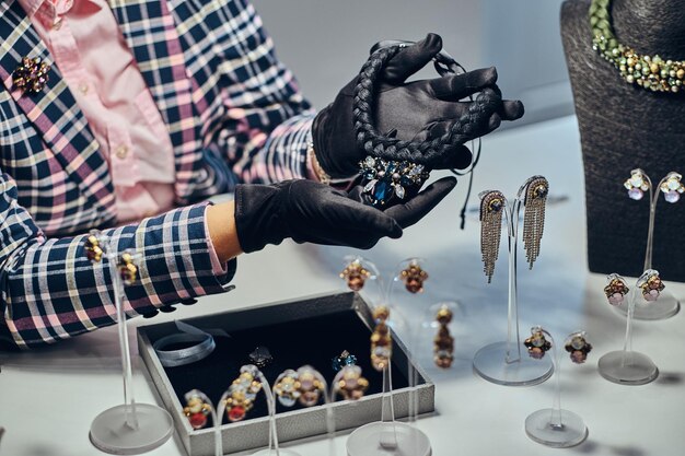Close-up foto van een juwelier die een kostbare ketting met edelstenen presenteert in een luxe juwelierszaak.