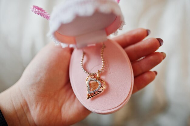Close-up foto van een vrouwelijke hand met juwelendoos met gouden hanger erin ingelegd met diamanten