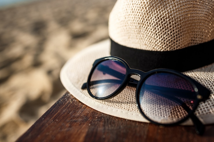 Gratis Foto close-up foto van hoed en bril op strand