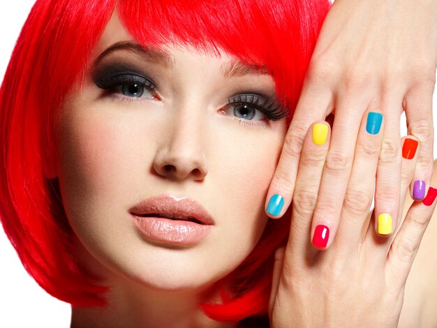 Close-up gezicht van een mooi meisje met heldere veelkleurige nagels.