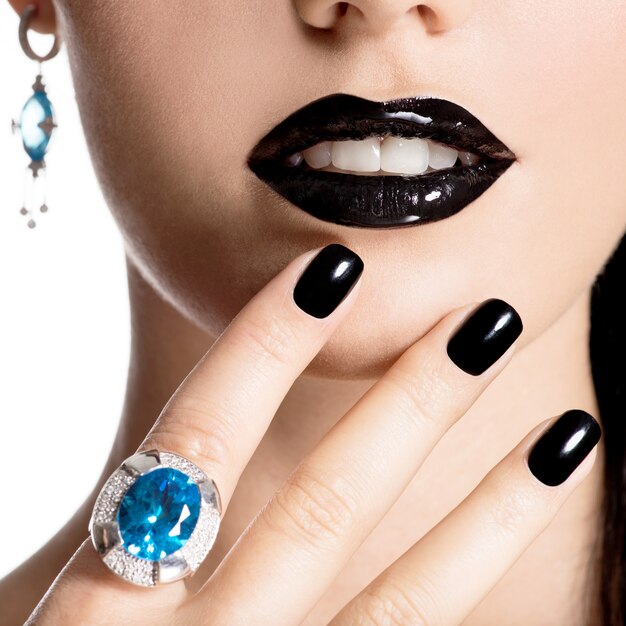 Close-up gezicht van jonge mooie vrouw met zwarte manicure en mode lichte make-up