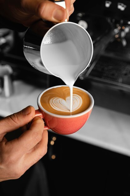 Close-up hand gieten melk in koffie