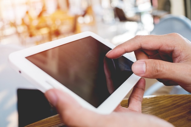 Close-up hand man met behulp van tablet in de koffiewinkel op tafel