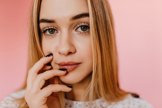 Close-up indoor portret van aantrekkelijke vrouw met groene ogen. portret van charmante jonge vrouw met blonde steil haar.