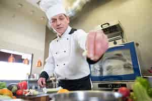 Gratis foto close-up op chef-kok koken in de keuken van het restaurant