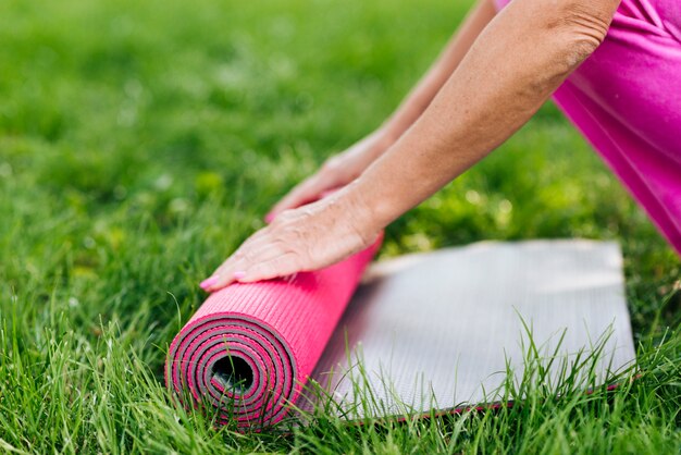 Close-up oude vrouw die een yogamat schikt