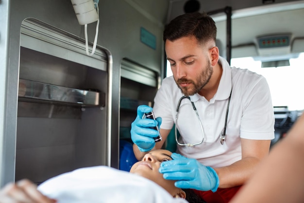 Close-up portret shot van een serieuze en gerichte paramedicus in een ambulancevoertuig met een gewonde patiënt Medische noodtechnicus gebruikt stethoscoop om de toestand te bewaken
