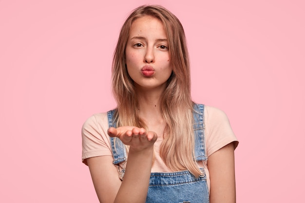 Close-up portret van aantrekkelijke jonge blanke vrouw blaast lucht kus op camera als flirt met haar vriendje