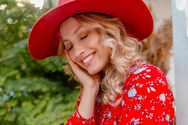 Close-up portret van aantrekkelijke stijlvolle blonde lachende vrouw in rode strooien hoed en blouse zomer mode outfit met glimlach