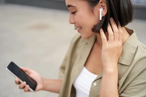 Close-up portret van aziatisch meisje kijken naar mobiele scherm luisteren muziek in koptelefoon vrouw met ea
