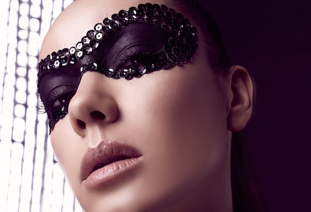 Close-up portret van charmante elegante brunette vrouw in pailletten masker poseren op zwart