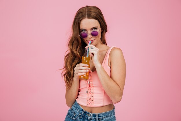 Close-up portret van charmante readhead vrouw in glazen, oranje frisdrank drinken