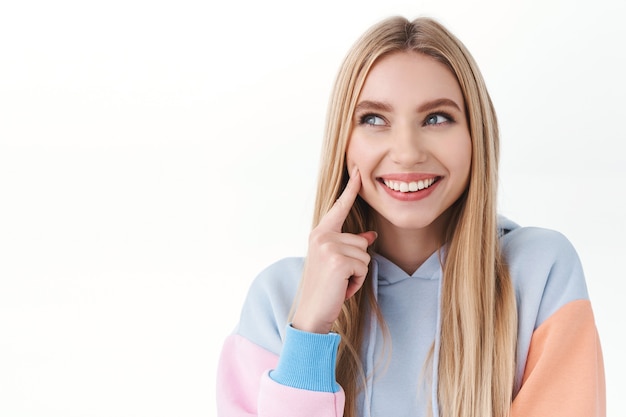 Close-up portret van een dom, vrouwelijk blond meisje, lachend en er dom uitziend, denkend, hebben een interessant idee