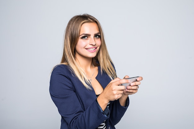 Close-up portret van een gelukkige jonge vrouw spelen op mobiele telefoon geïsoleerd