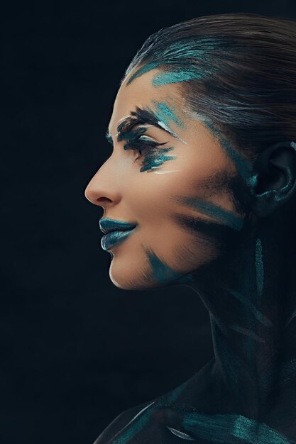 Close-up portret van een jong schoonheidsmeisje met creatieve make-up. Blauwe en zwarte schaduwen geschilderd op haar gezicht. Conceptueel idee.