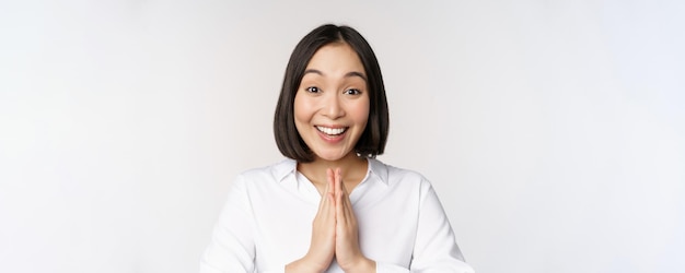 Close-up portret van een jonge Japanse vrouw die namaste toont, bedankt arigatou-gebaar dat over w . staat