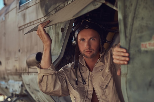 Close-up portret van een monteur in uniform en vliegend in de buurt, staande onder een oud bommenwerpervliegtuig in het openluchtmuseum.