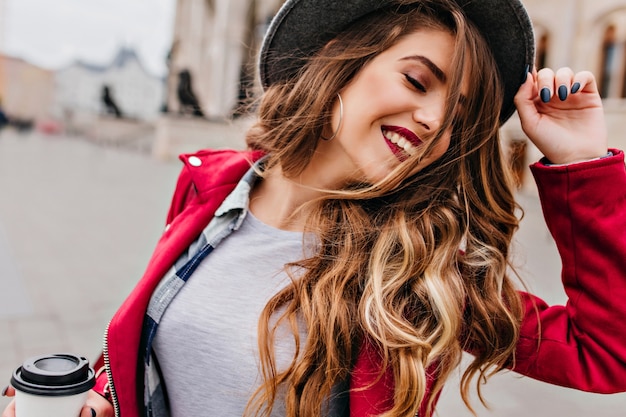 Close-up portret van fascinerende blanke vrouw met gouden golvend haar poseren met gesloten ogen op straat