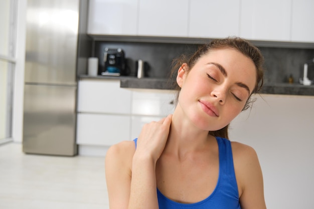 Gratis foto close-up portret van fitnessvrouw doet training vanuit huis en masseert nekoefening in de woonkamer sport- en welzijnsconcept