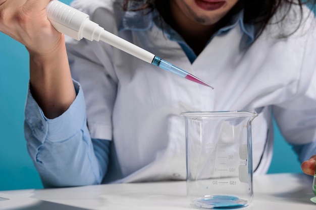 Close-up portret van gekke krankzinnige chemicus met behulp van druppelaar om experimentele chemische verbindingen te mengen na laboratoriumexplosie. dwaze gek uitziende wetenschapper met pipet die experimenten doet terwijl hij aan het bureau zit.
