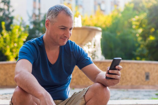 Close-up portret van gelukkig lachend veertig jaar oude Kaukasische man praten op een mobiele telefoon buiten