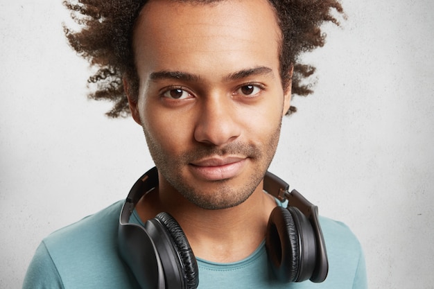 Close-up portret van gemengd ras donkere man met haren en donkere ogen, heeft koptelefoon
