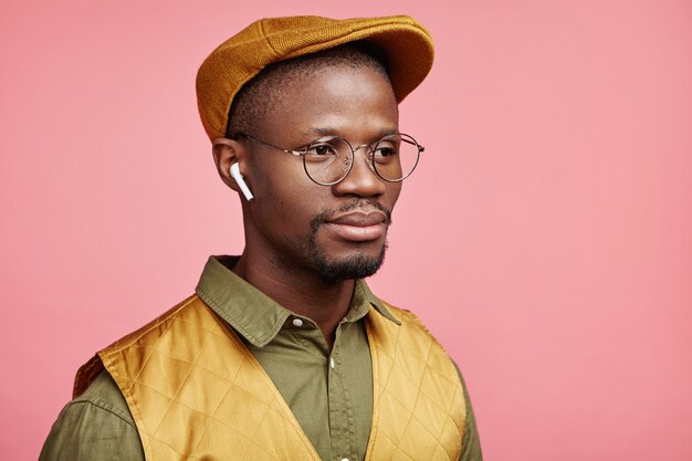 Close-up portret van jonge Afro-Amerikaanse man met hoed en draadloze koptelefoon