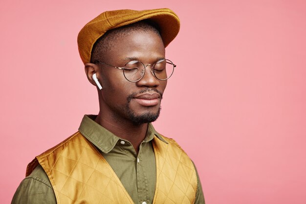 Close-up portret van jonge Afro-Amerikaanse man met hoed en draadloze koptelefoon