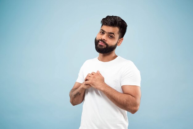 close-up portret van jonge Indiase man in wit overhemd. Poseren, staan en glimlachen, ziet er kalm uit.