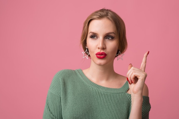 Close-up portret van jonge mooie vrouw geïsoleerd op roze achtergrond, denken, idee hebben, vinger omhoog houden, elegante stijl, rode lippen, lente modetrend, grappige gezichtsuitdrukking