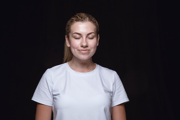 Gratis foto close-up portret van jonge vrouw geïsoleerd. vrouwelijk model met gesloten ogen. denken en glimlachen. gelaatsuitdrukking, concept van menselijke emoties.