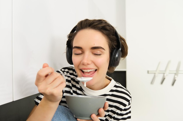 Gratis foto close-up portret van jonge vrouw geniet van het eten van haar ontbijt met granen met melk houdende lepel