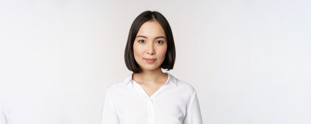 Close-up portret van Koreaanse jonge Aziatische vrouw die er zelfverzekerd en assertief uitziet op camera witte achtergrond Mensen uit het bedrijfsleven concept