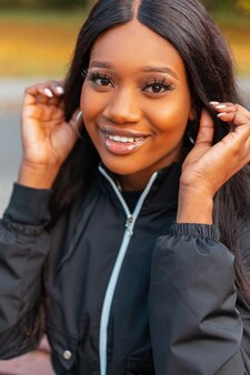 Close-up portret van mooie gelukkige afrikaanse vrouw met glimlach in casual modieuze jas buitenshuis