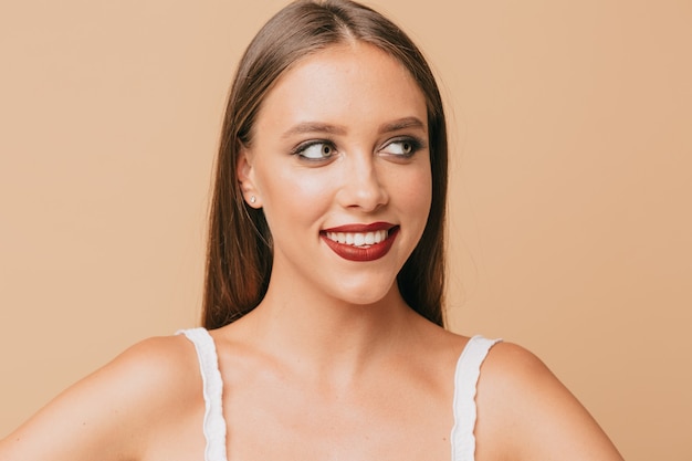 Close-up portret van mooie schattige vrouw met lichte make-up en lichtbruin haar op geïsoleerde muur met perfecte glimlach