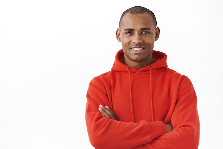 Gratis Foto close-up portret van professionele, succesvolle jonge afro-amerikaanse man in rode hoodie, kruis armen borst arms