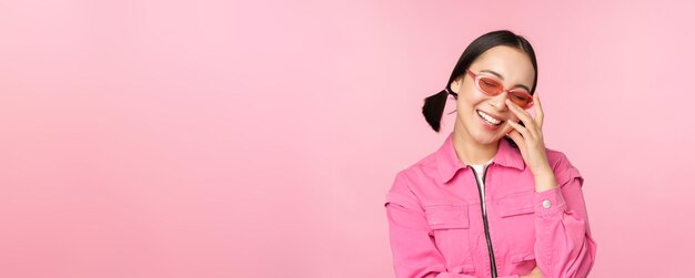 Close-up portret van stijlvolle Aziatische vrouw in zonnebril glimlachend op zoek gevleid lachen koket