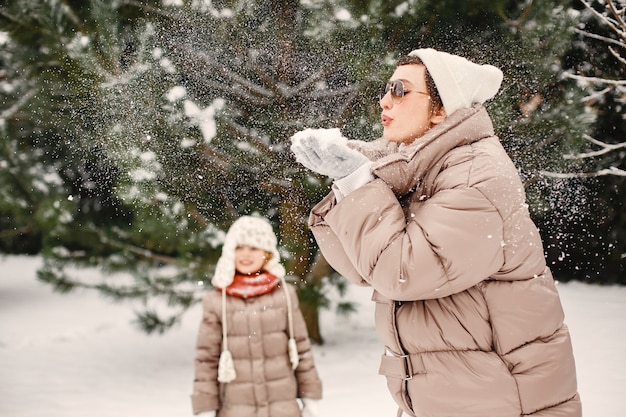 Close-up portret van vrouw in bruine jas in besneeuwde park met haar dochter