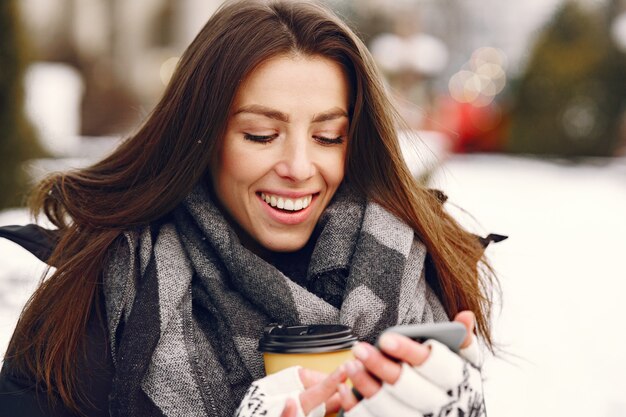 Close-up portret van vrouw in zwarte jas koffie drinken en smartphone te houden