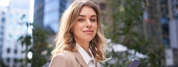 Gratis foto close-up portret van zakenvrouw jonge stagiaire loopt op straat naar kantoor en houdt sms-berichten op mobiele telefoons