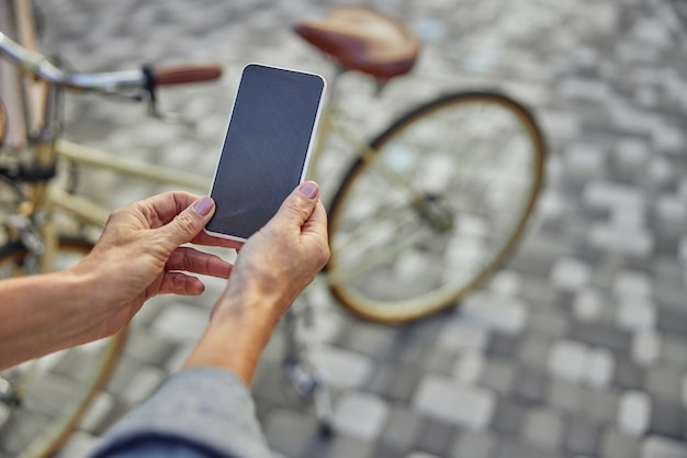 Close-up portret van zwart scherm van moderne mobiele telefoon in vrouw hand geïsoleerd op weg in het park
