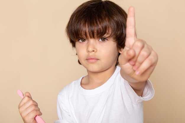 close-up, portretweergave poseren kind jongen schattig schattig lief in wit t-shirt op roze