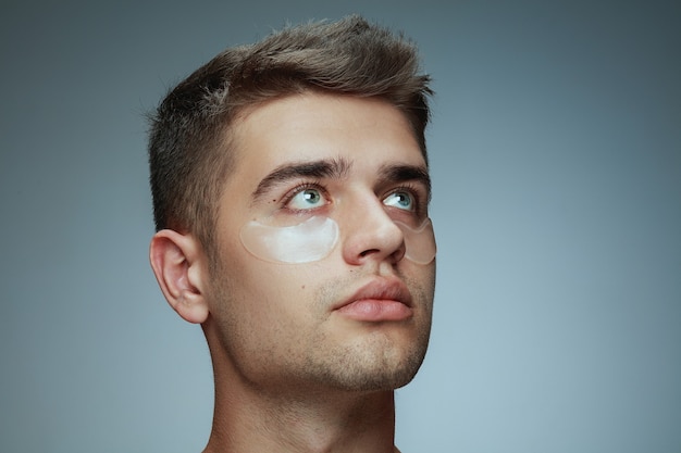 Close-up profiel portret van een jonge man geïsoleerd op grijze studio