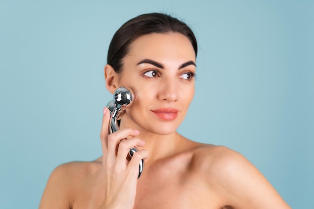 Close-up schoonheidsportret van een vrouw met perfecte huid en natuurlijke make-up, mollige naakte lippen, met een roller stimulator voor gezicht en nek