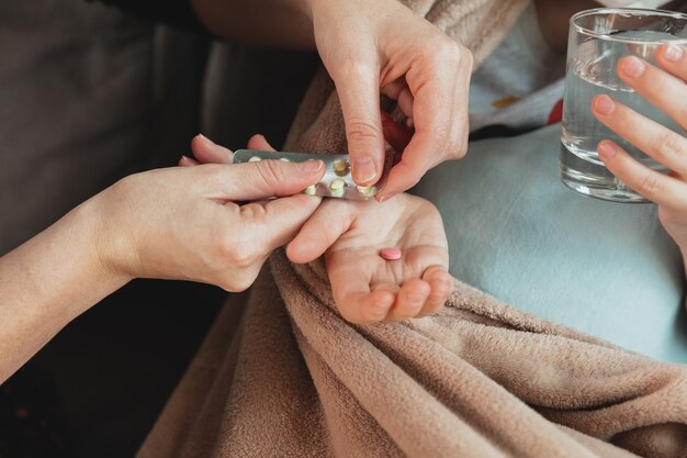 Close-up shoot van moeder die pillen geeft voor dochtertje die zich ziek voelt met coronavirus-symptomen in milde toestand