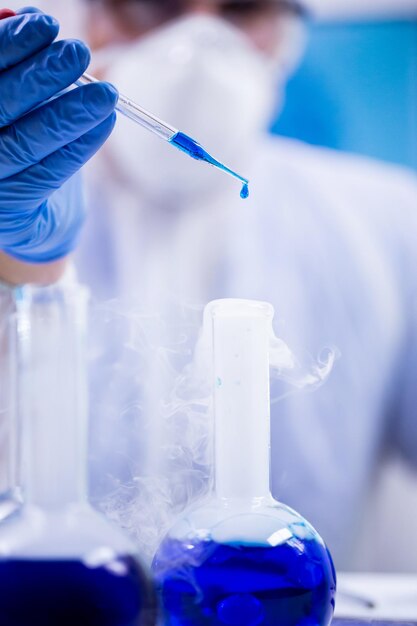 Close-up shot van blauwe oplossing die valt uit een pipet die wordt gebruikt door een wetenschapper in een onderzoekslaboratorium.